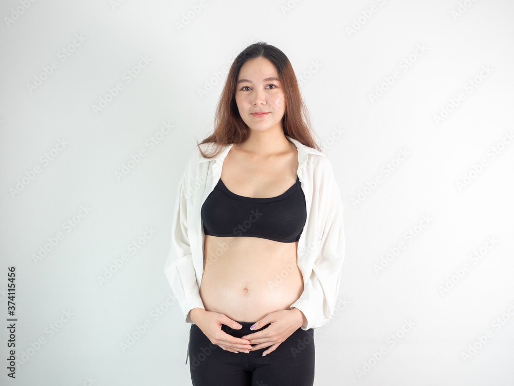 portrait of 4 months pregnant Asian woman in white bed room, Woman touching her abdomen belly on white background. portrait of 4 months pregnant Asian woman in white bed room, Woman touching her abdomen belly on white background.