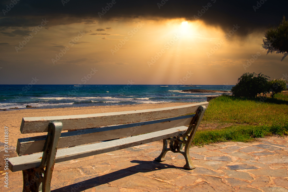 A lonely bench by the sea at sunset on the island Crete