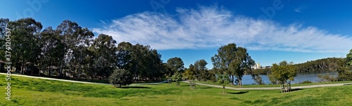 Beautiful panoramic view of a park with green grass, tall trees, walking trail and rainbow look-alike clouds, Reid Park, Parramatta Cycleway, Rydalmere, Sydney, New South Wales, Australia 