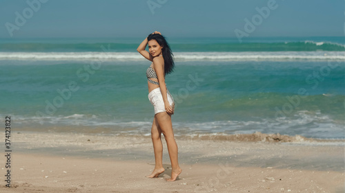 Young balinese girl in full growth on the beach on a sunny day