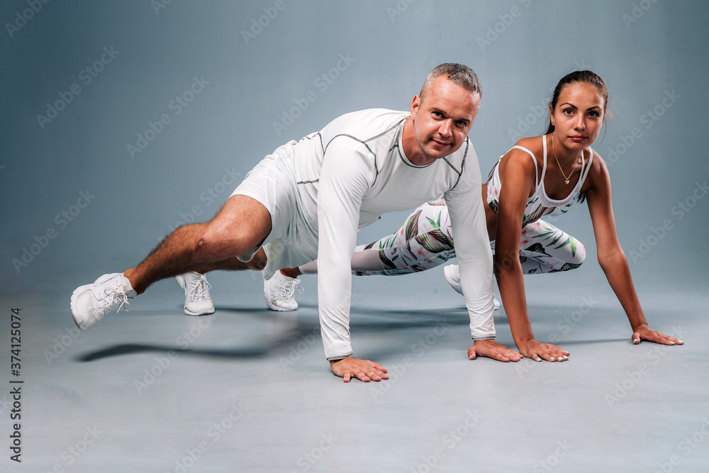 Obraz premium Young sports couple engaged in fitness on a gray background