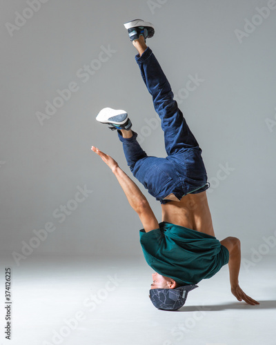Fotografía Cool guy breakdancer dancing on one hand isolated on gray background