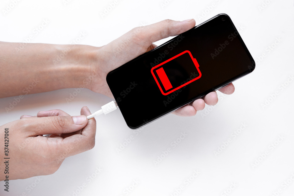 Hand charges smartphone on white background. View from above. Charge your phone, sign that your phone is low. Close the USB Type-C (USB-C) mobile phone charger. Charger with USB Type C cable and phone Hand charges smartphone on white background. View from above. Charge your phone, sign that your phone is low. Close the USB Type-C (USB-C) mobile phone charger. Charger with USB Type C cable and phone