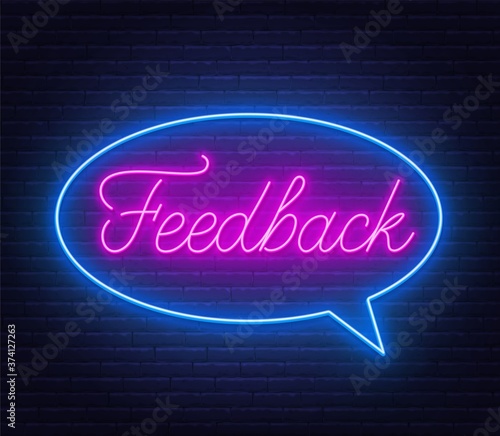 Feedback neon sign in speech bubble frame on brick wall background.