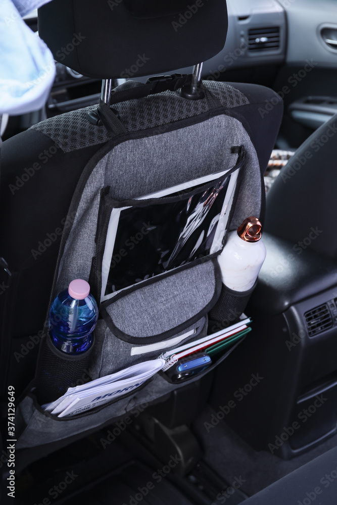 Travel organizer with different things on car seat in salon
