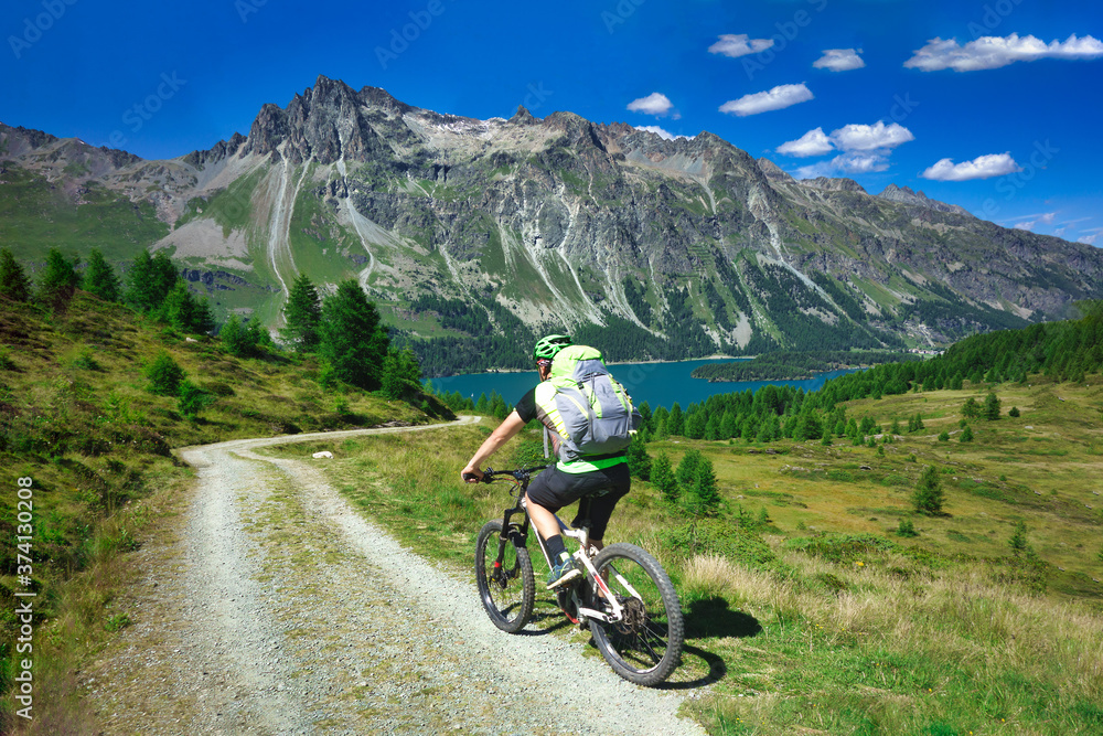 Biker on mountain dirt road in beautiful landscape on the alps
