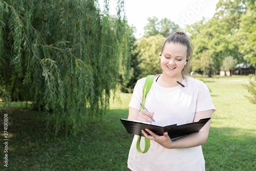 Fat woman writing personal workout plan at park