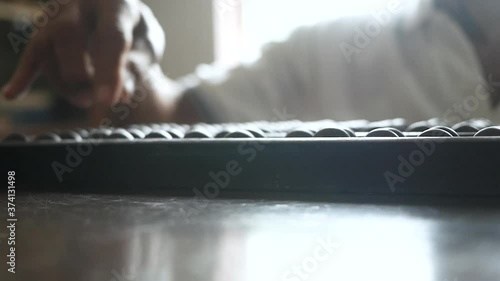 Close up of senior hand using chinese abacus or old antique calculator on wooden table. photo