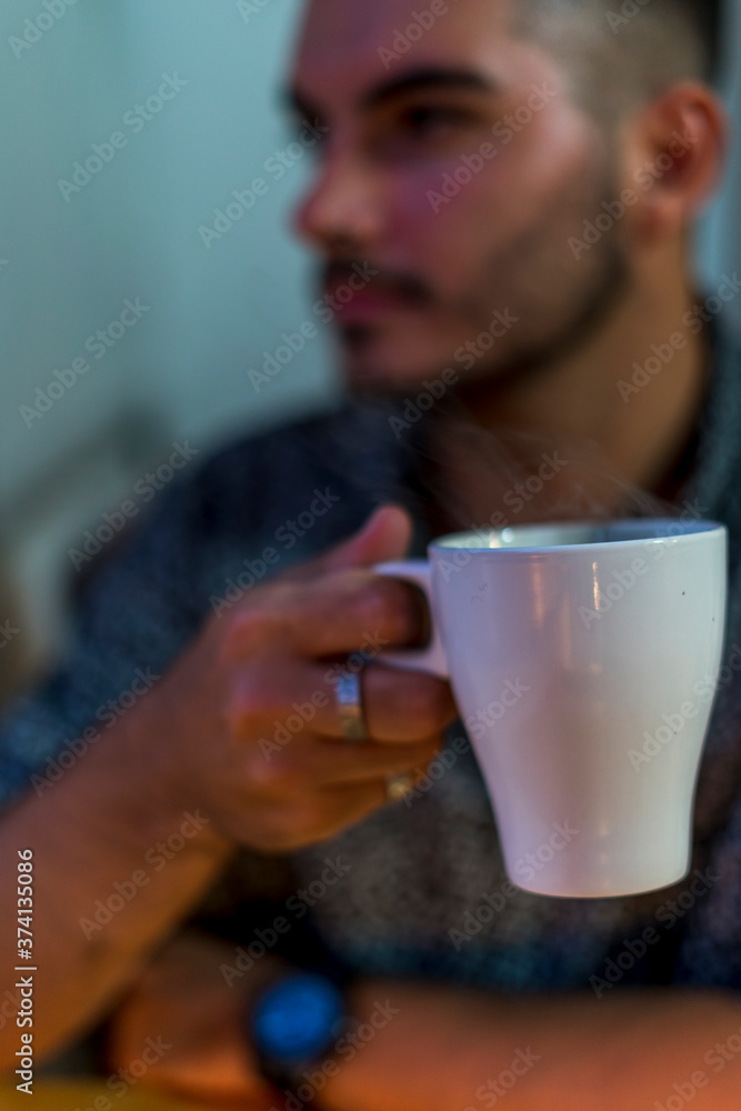 Joven con taza de cafe trabajando en el ordenador junto a la ventana Joven con taza de cafe trabajando en el ordenador junto a la ventana