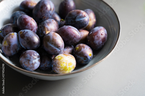 fresh plum fruits in grey bowl on table