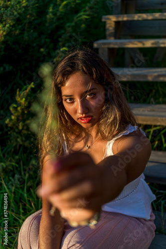 Chica joven posando en unas escaleras de madera al tardecer en la playa photo