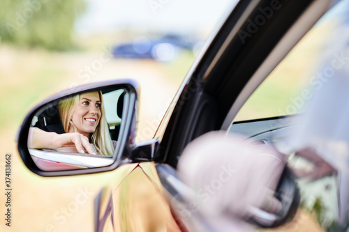 Reflection in wing mirror of smiling woman driving car © gpointstudio