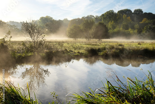 Early morning mist over the meadows on the River Wey in Godalming, Surrey, on a cold autumn morning.