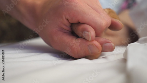 Wallpaper Mural Young man holds and gently touches hand of sick mature woman lying in bed hospital. Grandson comforts wrinkled arm of his elderly grandmother in medical clinic. Son shows care and love to his parent Torontodigital.ca