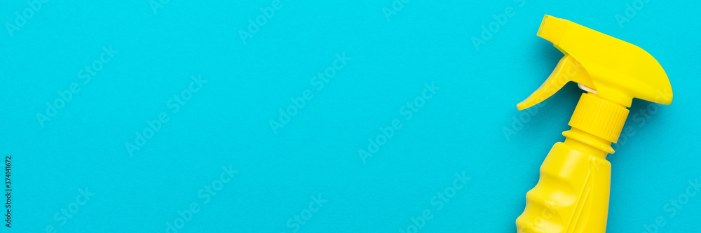cleaning spray on the turquoise blue background with copy space. flat lay image of yellow plastic dispenser