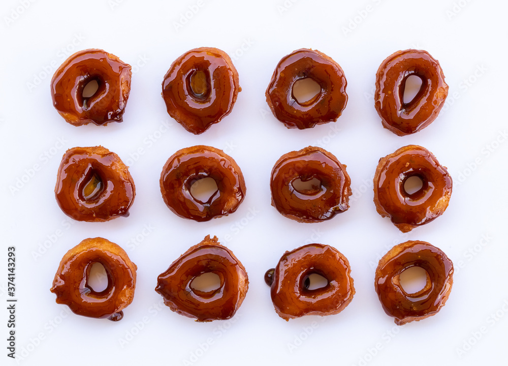 A row of fried Thai donuts coated with burnt sugar on a white background. A row of fried Thai donuts coated with burnt sugar on a white background.