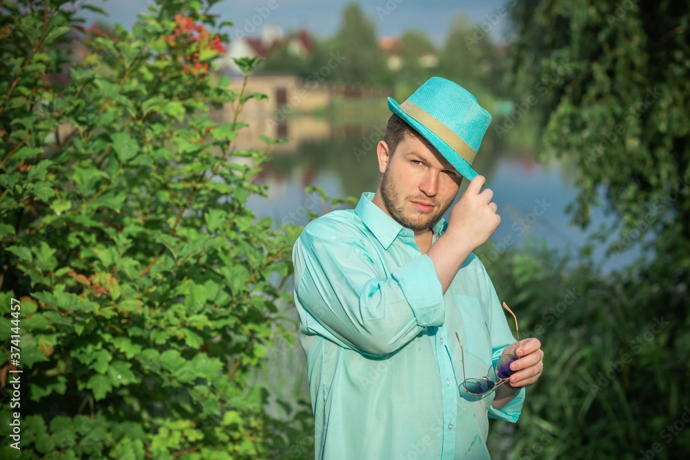 Young guy in turquoise shirt fashion outfit for men, clothes concept. Man rest at nature in fancy style Young guy in turquoise shirt fashion outfit for men, clothes concept. Man rest at nature in fancy style