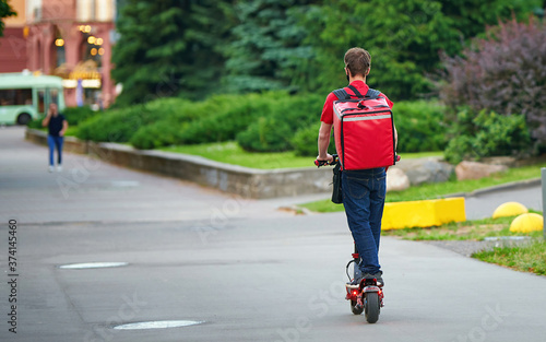 Wallpaper Mural Boy delivering hot food to costumers. Delivery man deliver fresh hot food, rides fast on an electric scooter. Delivery service from cafes and restaurants. Courier deliver food on electric scooter Torontodigital.ca