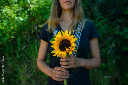 Young woman standing outdoors with a sunflower