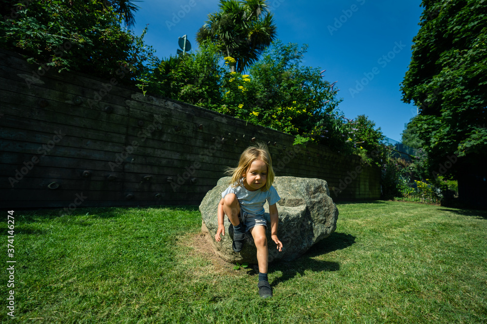 Little preschooler sitting on a rock in the park Little preschooler sitting on a rock in the park