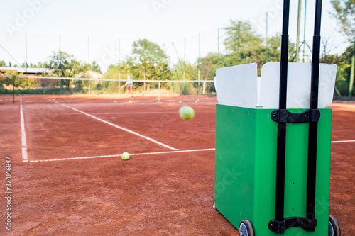 Ball machine on slag tennis court.