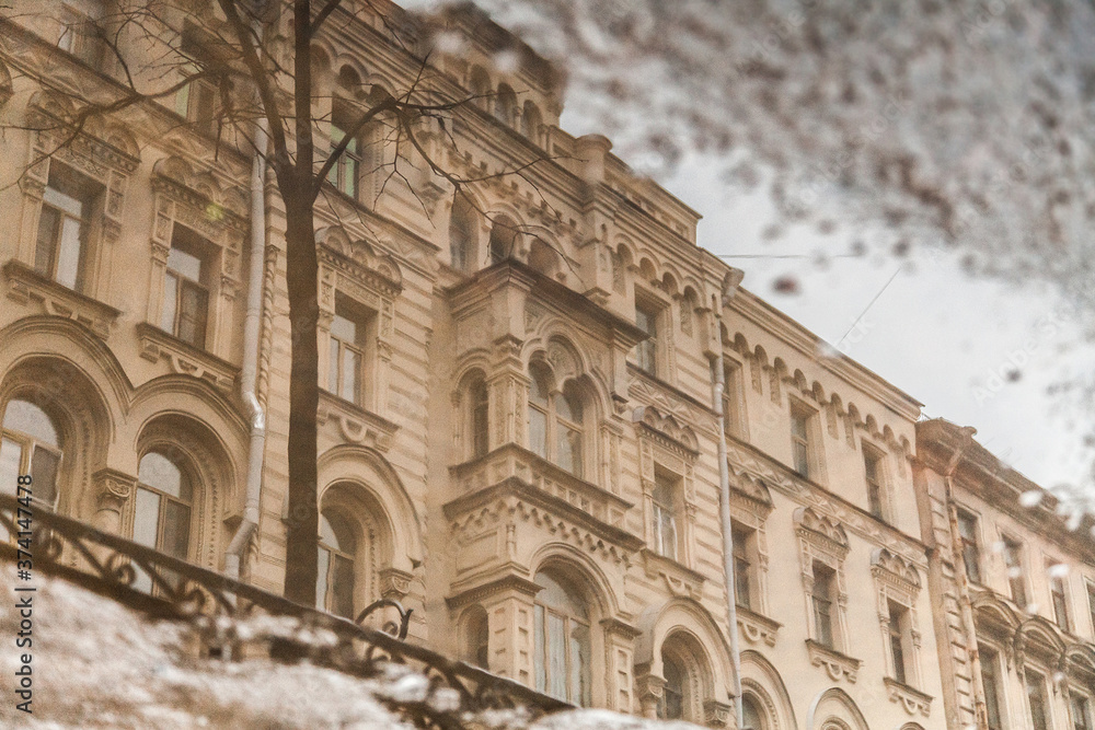 Fototapeta premium Facade of a vintage residential building reflected in a freezing puddle