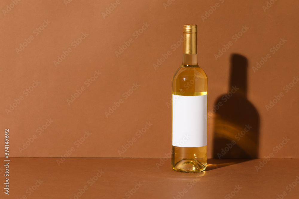 Fototapeta premium Bottle of wine with blank label on color background. Mockup for design