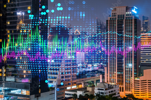 Stock market graph hologram  night panorama city view of Bangkok  popular location to gain financial education in Asia. The concept of international research. Double exposure.