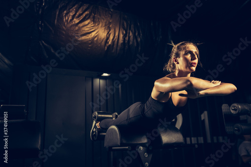 Flexible  strong. Young caucasian female athlete training in gym  doing strength exercises  practicing. Beautiful girl works on her upper and lower body. Fitness  wellness  sport  healthy lifestyle