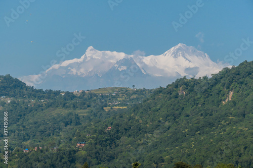 Close up view on snow capped Himalayas with Mt Fishtail (Machapuchare) between, seen from Phewa Lake in Pokhara, Nepal. Sharp and dangerous slopes. There is a hill in front of it, covered with forest © Chris