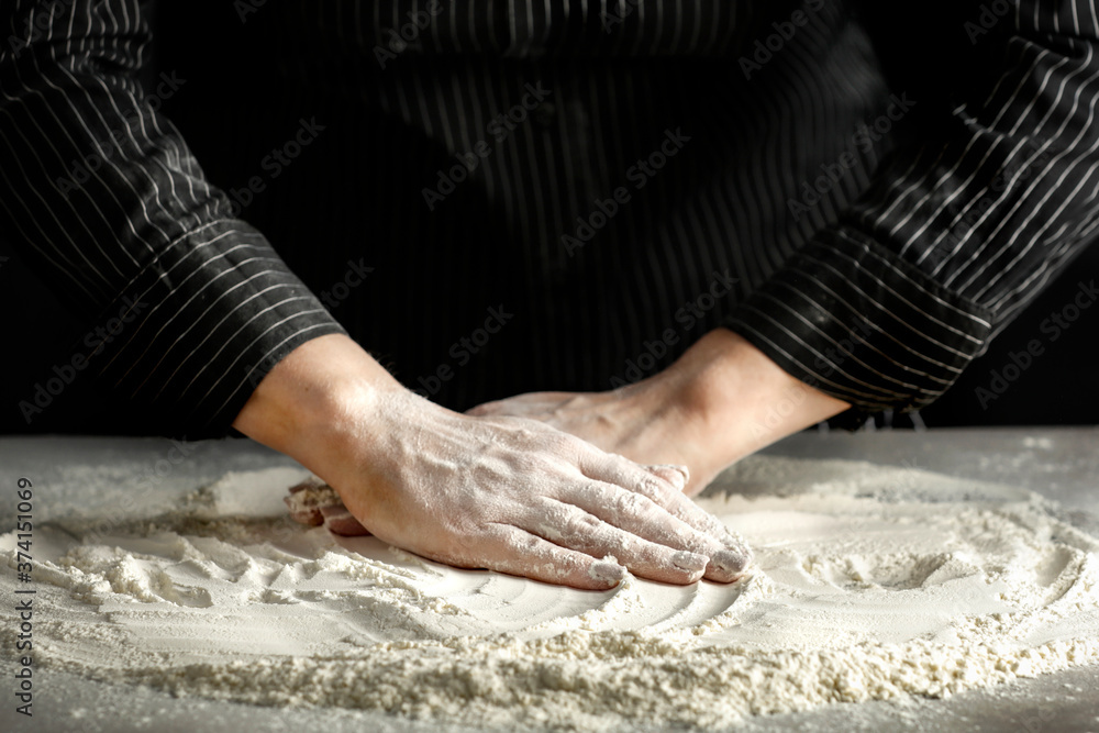Flour on a wooden table surrounded by female hands with free space for an advertising product