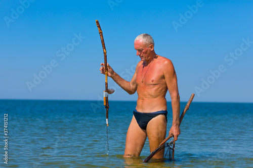Man with a homemade spear at the ready before throwing. He hunts stingrays that have swum in shallow water.