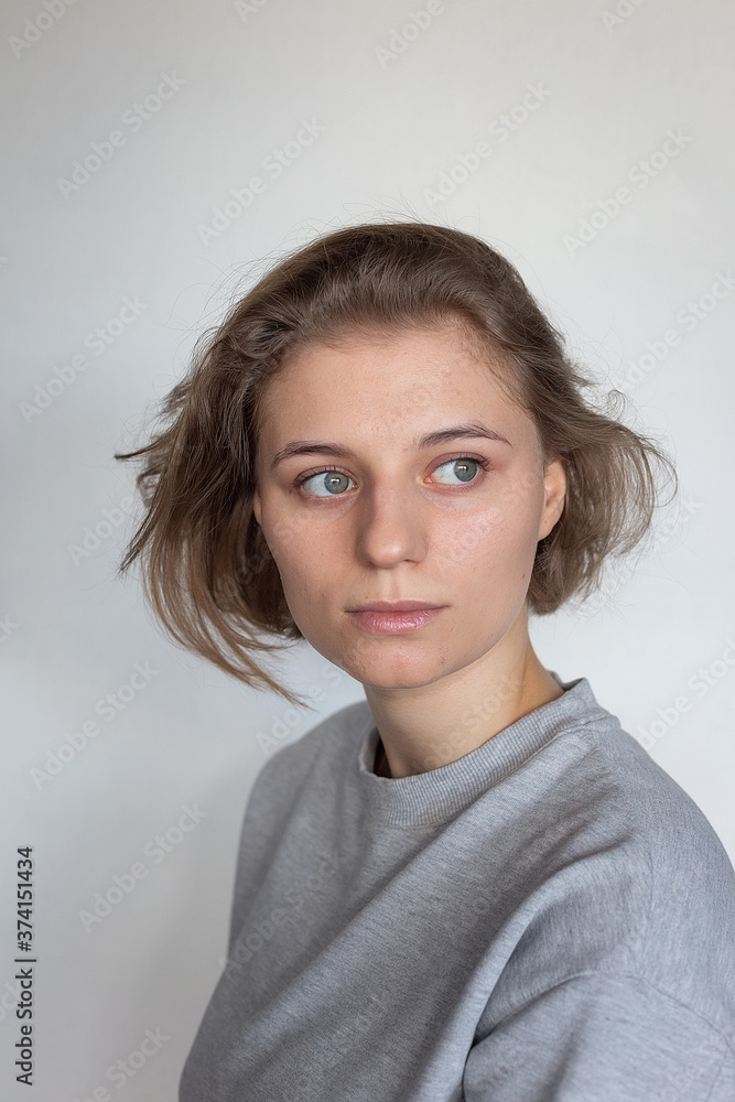 portrait of caucasian woman with clean skin and short hair posing in gray sweatshirt on white background, looking away. model tests of pretty girl, close up. attractive female poses portrait of caucasian woman with clean skin and short hair posing in gray sweatshirt on white background, looking away. model tests of pretty girl, close up. attractive female poses
