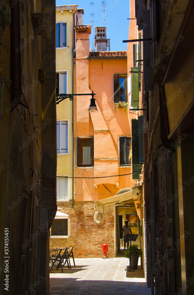a narrow alley in Venice opening into a plaza