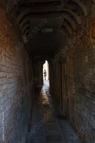 someone walking into a narrow Venetian alley