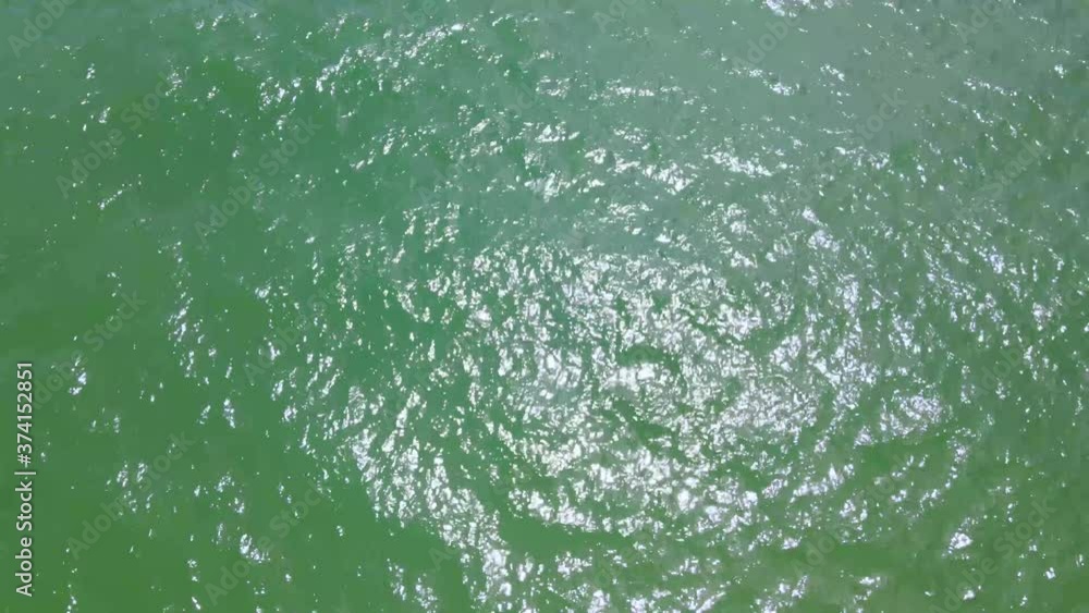 Aerial top down view from high altitude of green sea water texture. The camera flies over the water, a view of the water surface. Background of the water surface. 4K aerial view Phuket Thailand. Aerial top down view from high altitude of green sea water texture. The camera flies over the water, a view of the water surface. Background of the water surface. 4K aerial view Phuket Thailand.