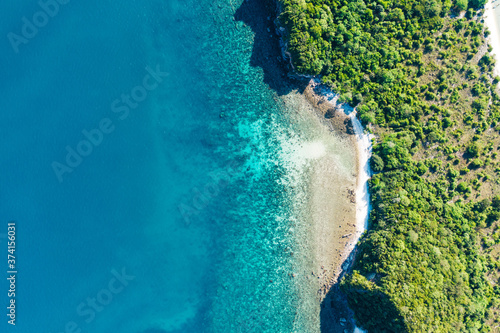 Fototapeta Naklejka Na Ścianę i Meble -  Aerial scenery view of picturesque island with crystal azure water and green vegetation.Bird's eye view of paradise beach shoreline, beautiful touristic destination for summer vacations,