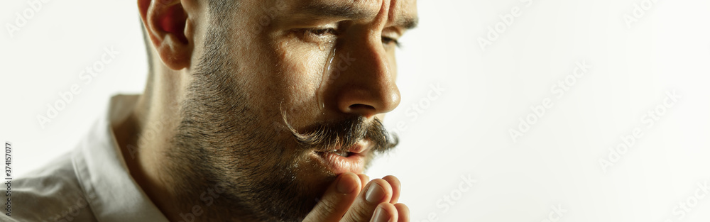 Obraz premium Praying. Caucasian young man's close up cropped shot on studio background, flyer. Concept of human emotions, facial expression, sales, ad. Copyspace. Beautiful male model with bright expression.