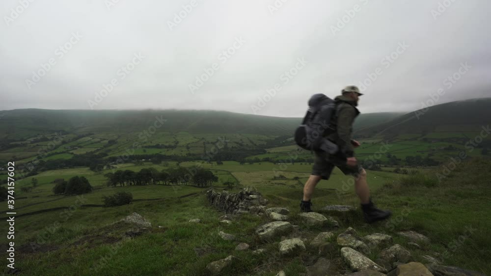 Man walking through the Peak District in overcast cloudy weather Man walking through the Peak District in overcast cloudy weather