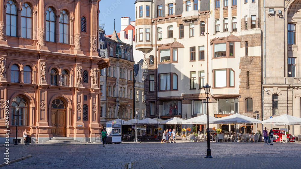 Riga. Buildings and cozy streets of the old city. Variegated facades, stone paving stones. Cafes and restaurants. People walk the streets in the evening. Latvia. Summer 2020
