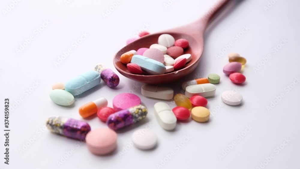 close up of colorful pills on spoon on white background close up of colorful pills on spoon on white background