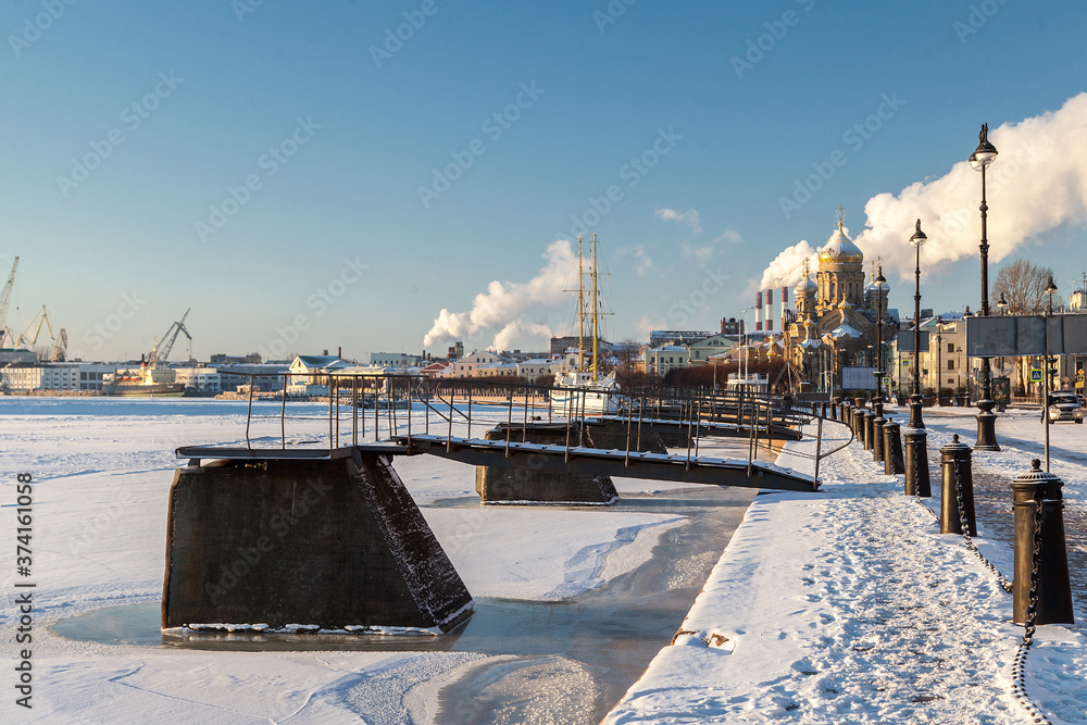 Winter cityscape of the Lieutenant Schmidt embankment in St. Petersburg with a sailboat in the winter parking lot and a view of the Assumption Church