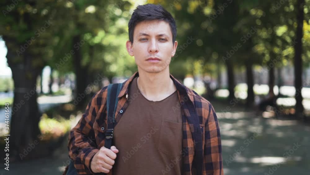 a young guy stands in the park calmly looking at the camera. High quality 4k footage a young guy stands in the park calmly looking at the camera. High quality 4k footage