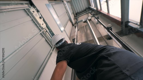 Young man mechanic engineer working doing maintenance on elevator lift at construction site slow motion photo
