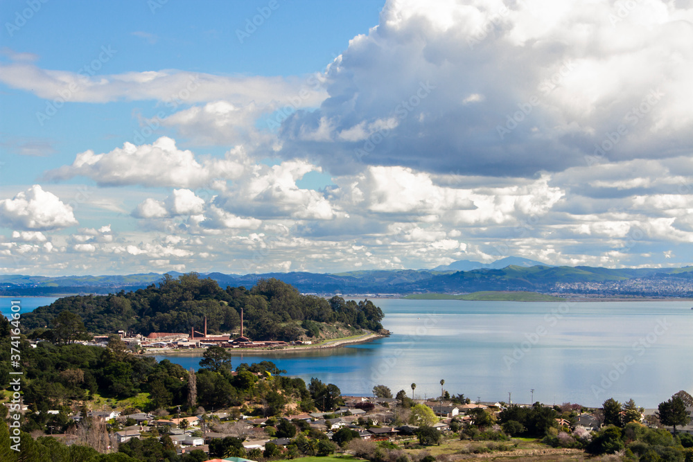 Massive clouds sweep through blue skies over the San Rafael Bay section of San Francisco Bay with neighborhoods, rock quarry and calm blue waters  Royalty free stock photo