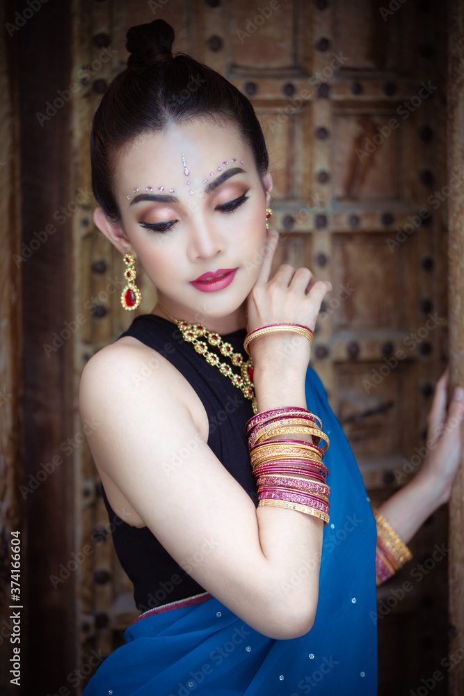 Naklejka premium Portrait of young asian girl with kundan jewelry set and traditional hindu Indian costume saree and lehenga dress model