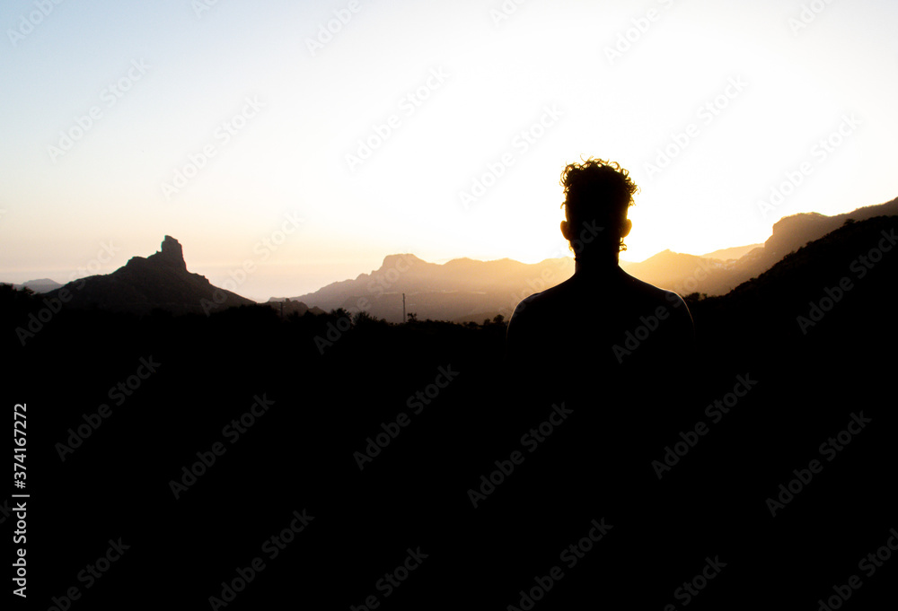 silhouette of a man sitting on a rock