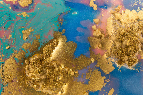Piles of gold sequins on blue liquid ink background. Abstract pattern.