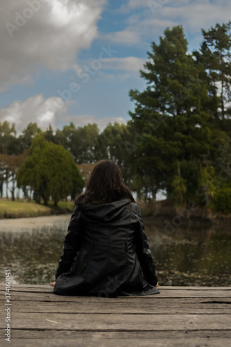 girl sitting on a pier looking at the trees, relaxation concept, vacation advertising, travel campaign