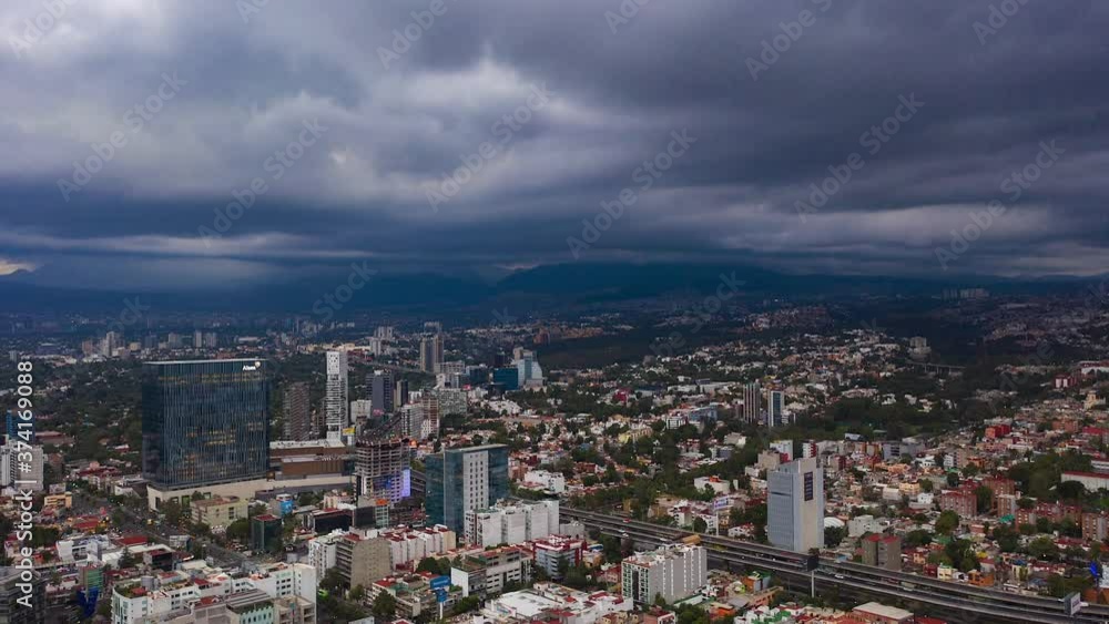 Aerial dronelapse view of dark, storm clouds moving over buildings and a busy road, in Mexico city, America - Reverse, hyper lapse, drone shot Aerial dronelapse view of dark, storm clouds moving over buildings and a busy road, in Mexico city, America - Reverse, hyper lapse, drone shot